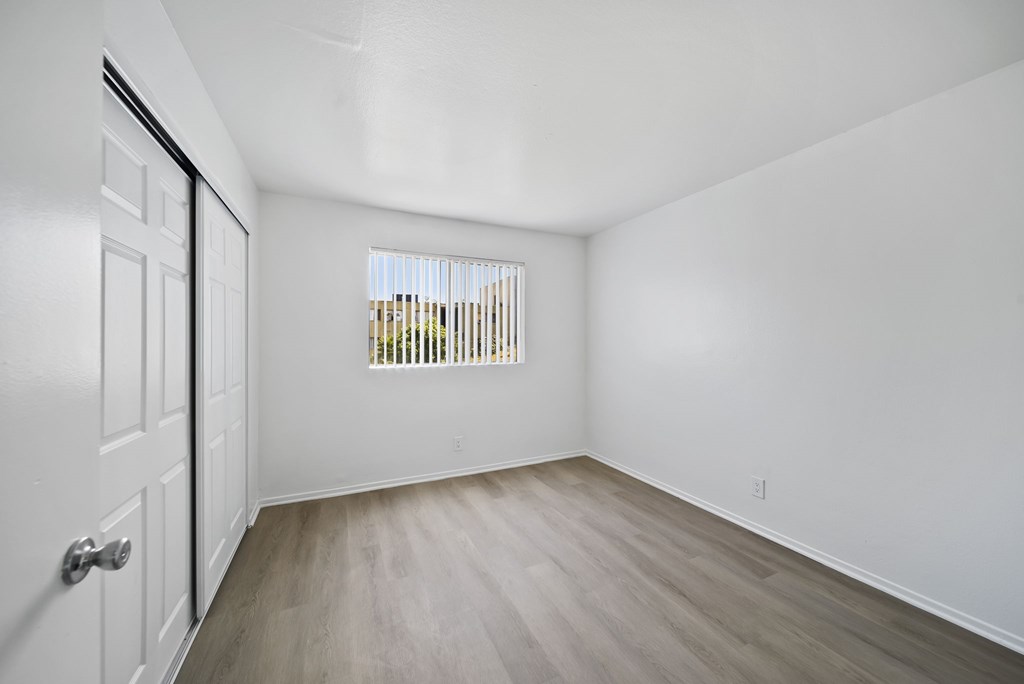 A room with a white door and a window with blinds.