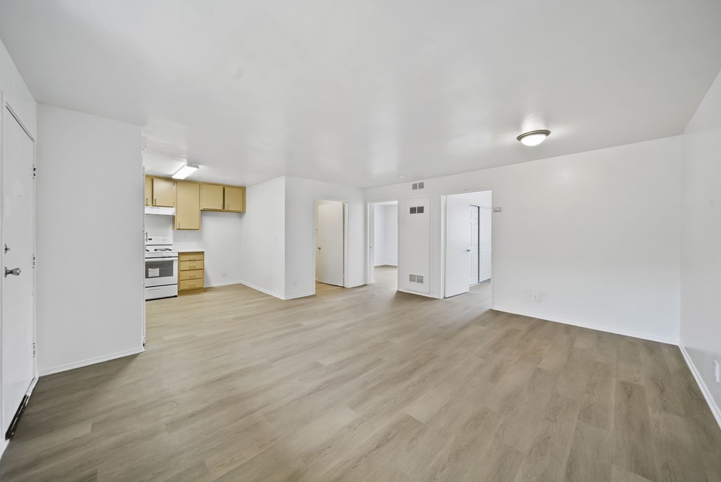 A spacious room with wooden flooring and white walls.