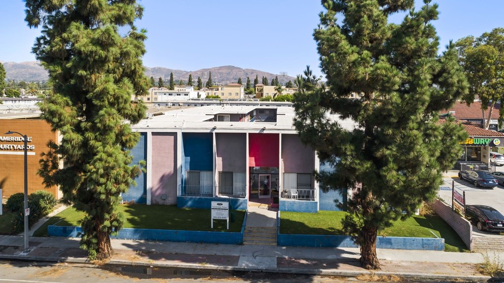 A building with a blue and pink facade is surrounded by trees.