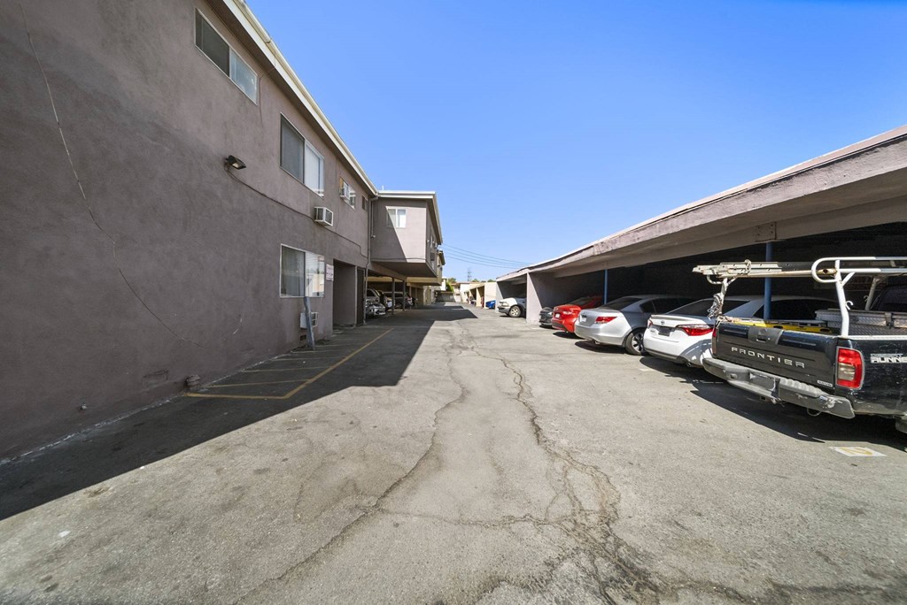 A parking lot with several cars and a building on the left.