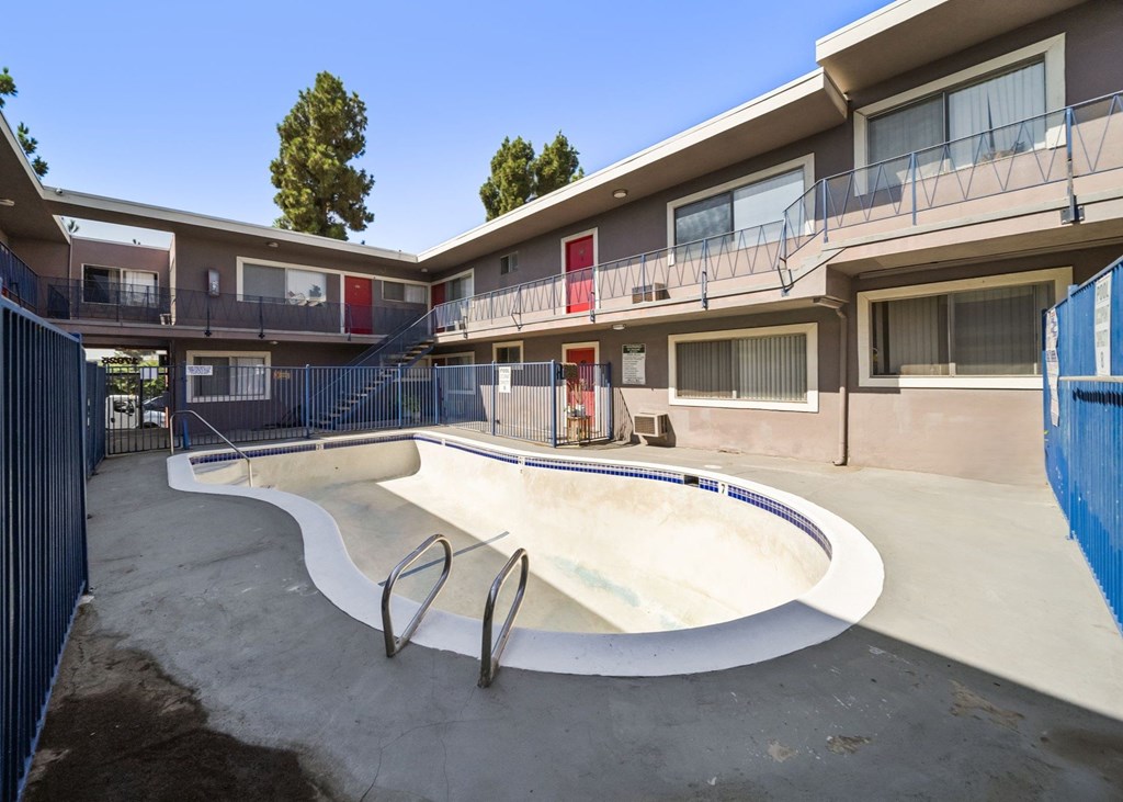A skate park with a concrete bowl and a blue fence.