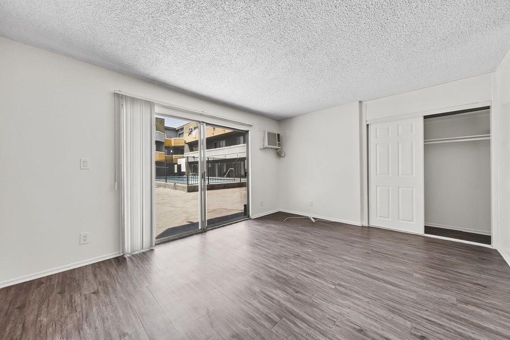 A room with a sliding glass door and wood flooring.