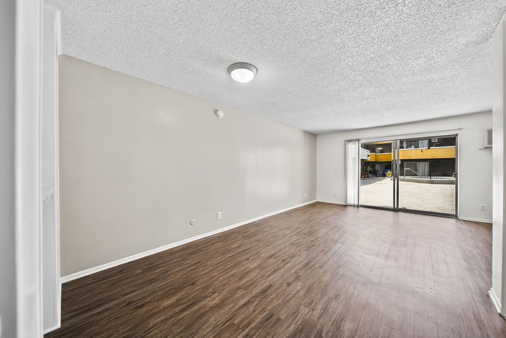 A room with wooden flooring and a sliding glass door.