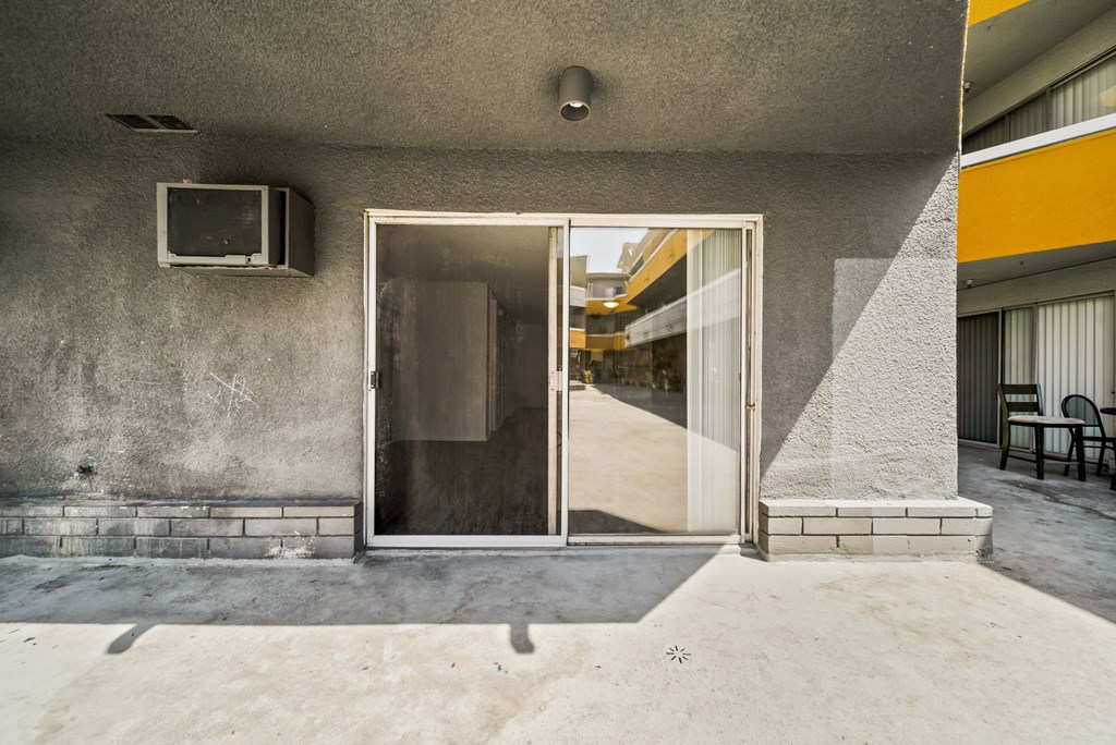 A concrete building with a glass door and a small window on the wall.