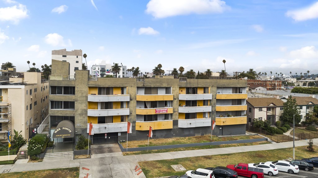 A parking lot with cars and a multi-story building in the background.