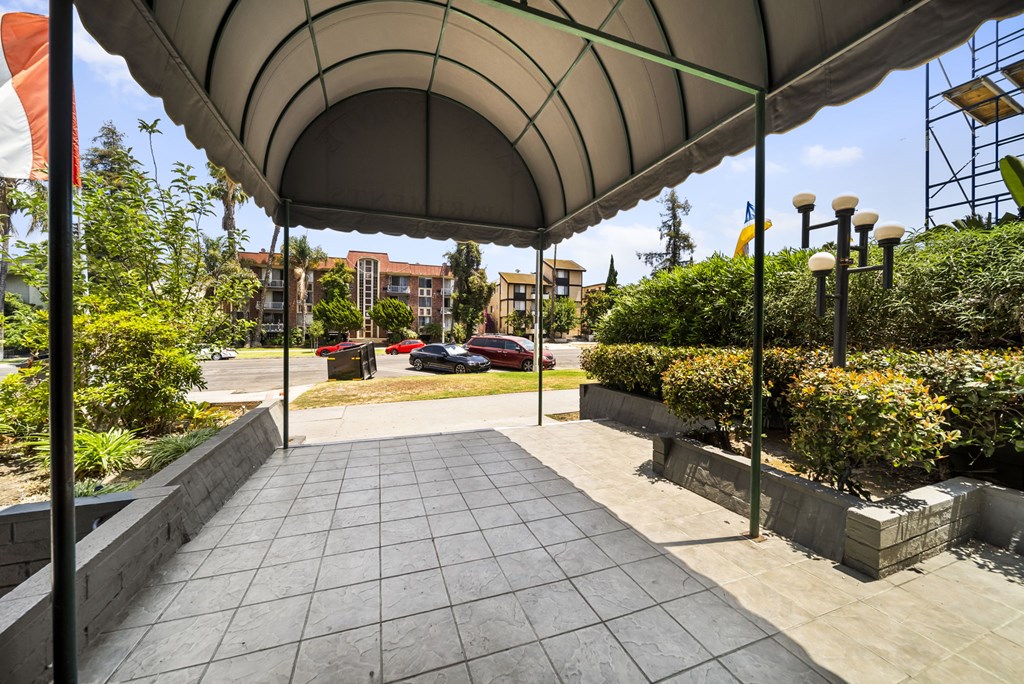 A walkway with a canopy and a car parked in the background.