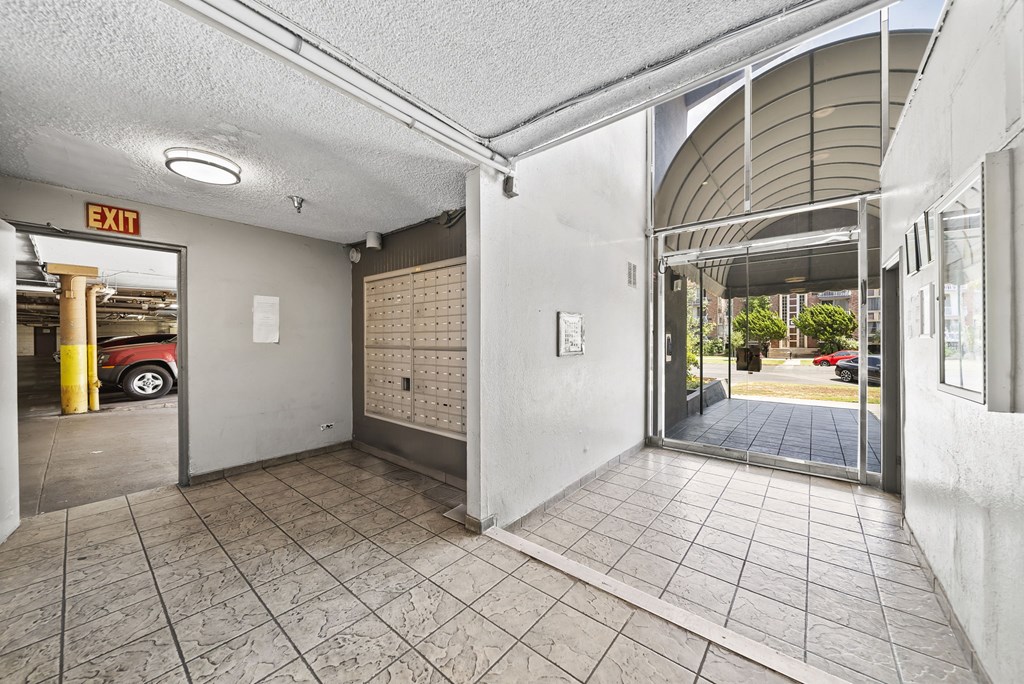A parking garage with a red car and an exit sign.