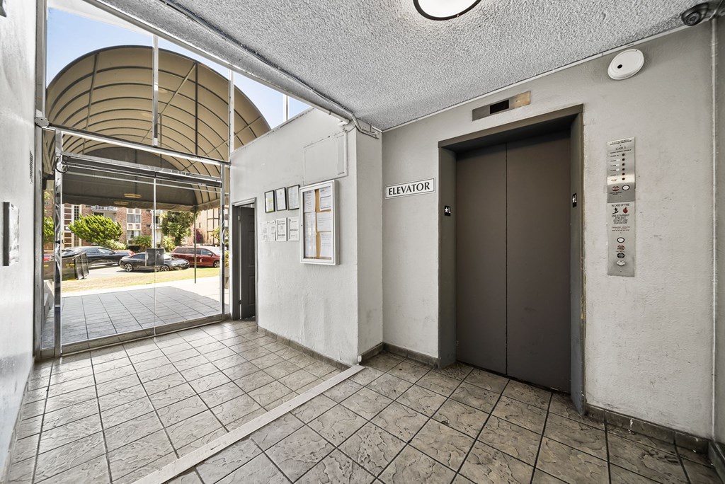 A hallway with a brown elevator and a white wall.
