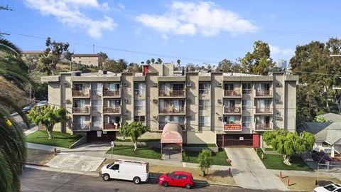A red car is parked in front of a white van.