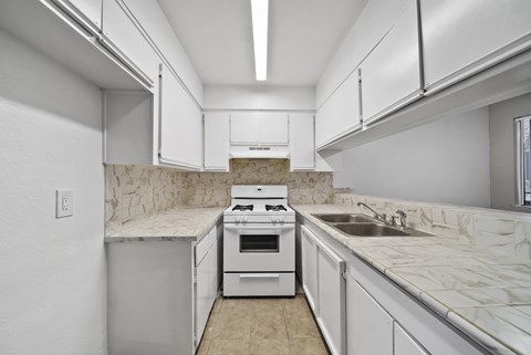 A kitchen with white cabinets and a marble countertop.
