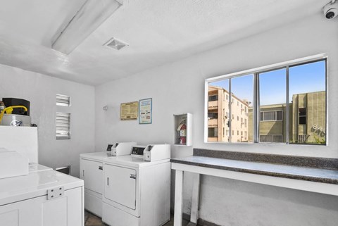 A white room with a large window and a white fridge.