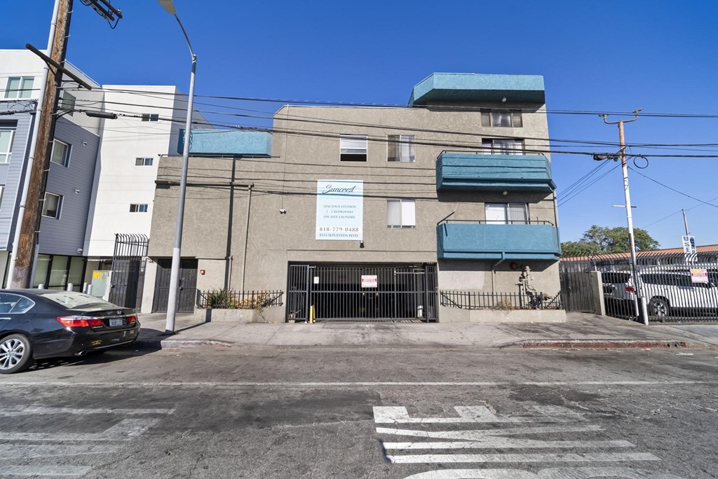 A car is parked in front of a building with a blue awning.