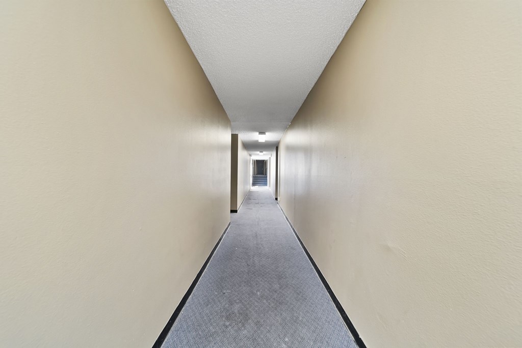 A long hallway with a carpeted floor and white walls.
