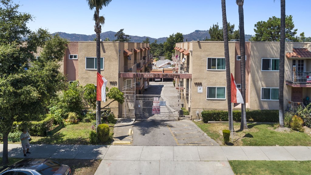 A gated entrance to a residential complex with a flag on a pole.