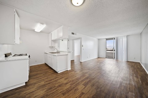 A white kitchen with wooden floors and a large open space.