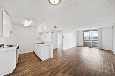 A white kitchen with wooden floors and a large window.