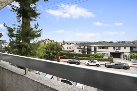 A view of a street with cars and buildings from a balcony.
