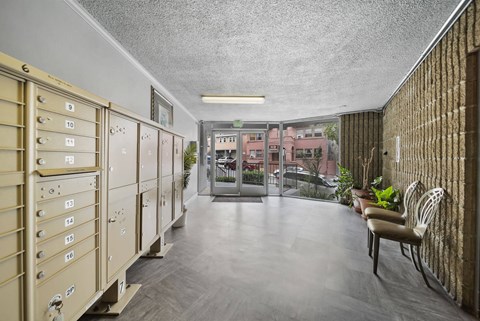 A long hallway with mailboxes on the left and a bench on the right.