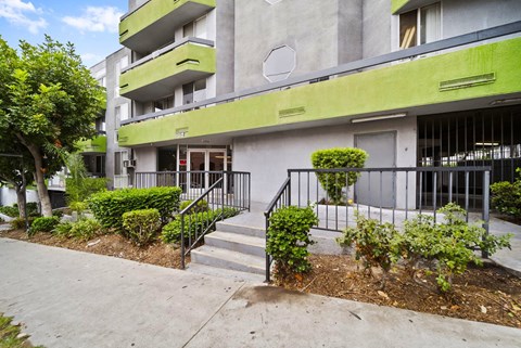 A modern building with a green trim and a black railing on the stairs.