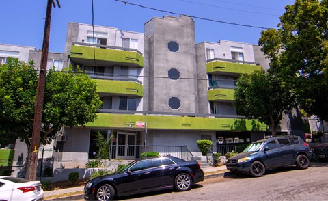 A black car is parked in front of a grey and green building.
