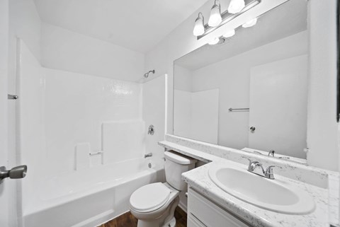 A white bathroom with a toilet, sink, and bathtub.