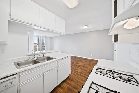 A modern kitchen with white cabinets and a wooden floor.
