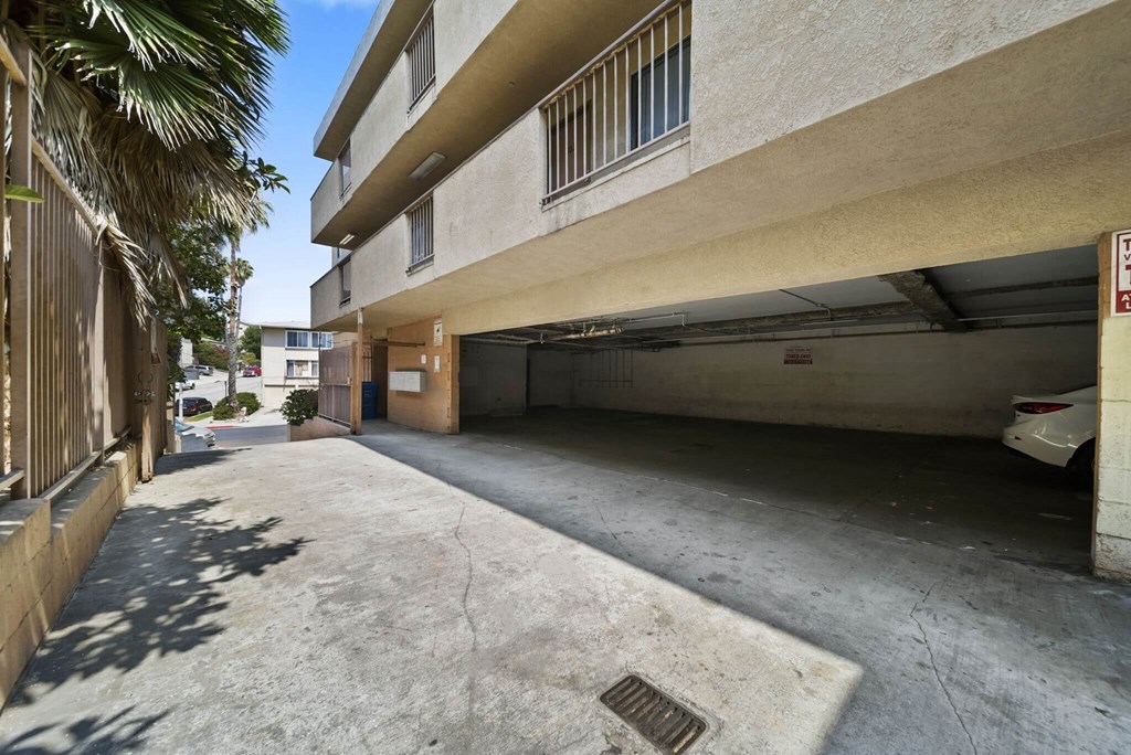 A car is parked in a garage under a building with a sign on the wall.