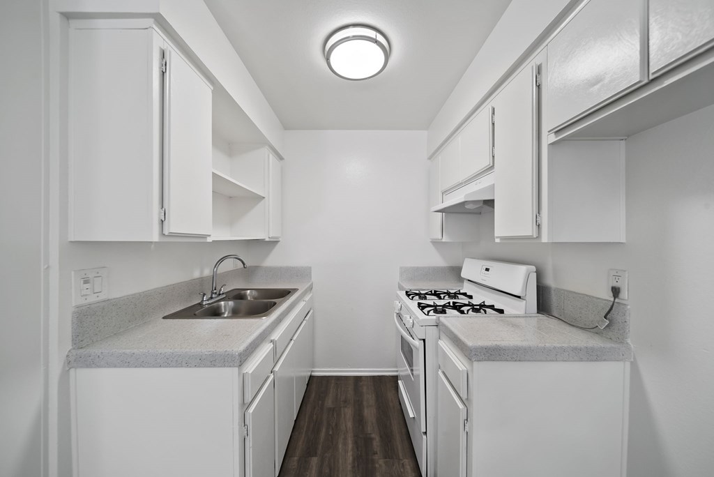 A small white kitchen with a sink and stove.