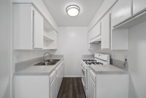 A small white kitchen with a sink and stove.