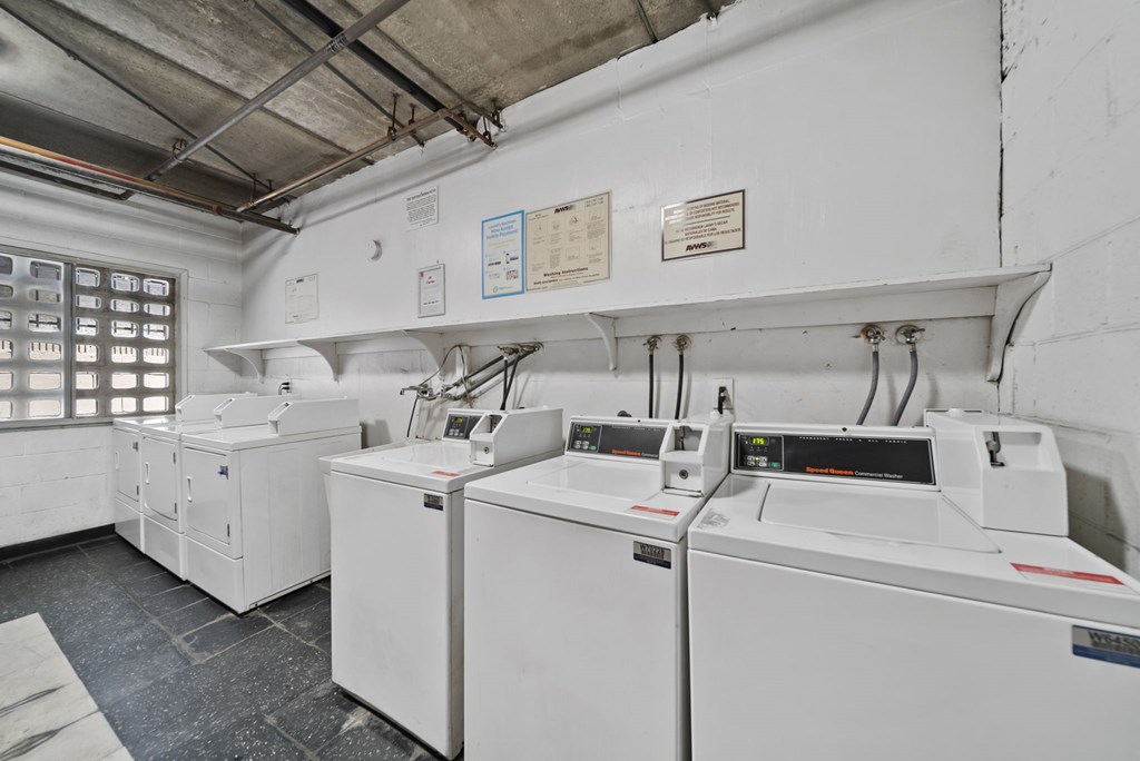 A white industrial room with a row of machines on the right and a window on the left.