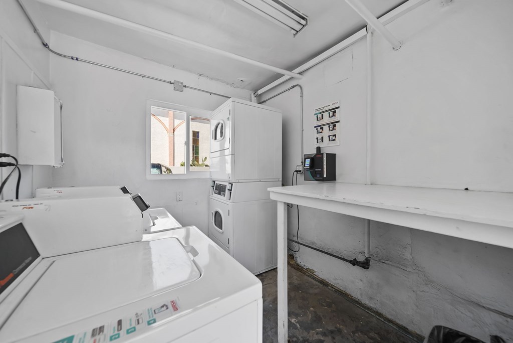 A white washing machine is in a room with a white wall.