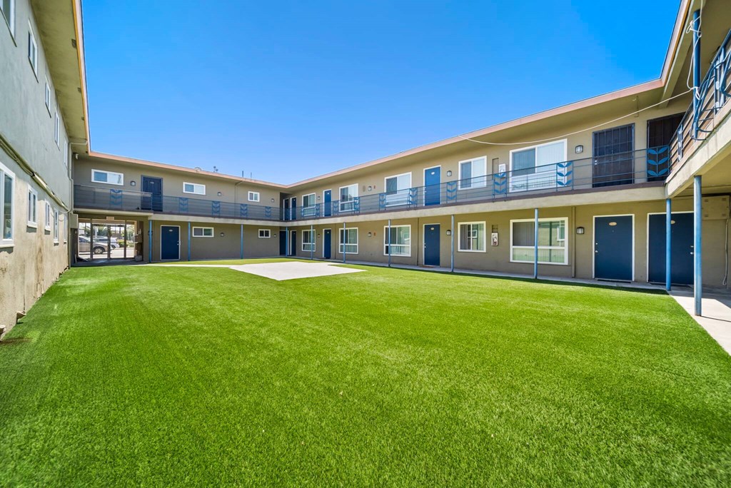 A sunny day at the courtyard of a building with blue doors and windows.