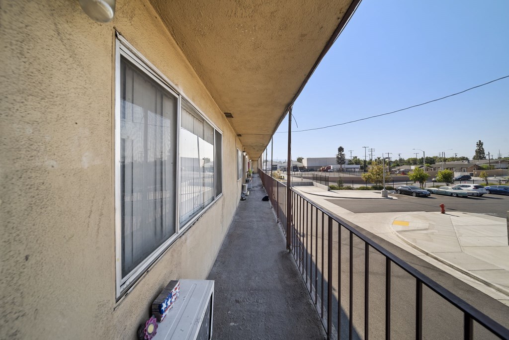 A balcony with a bench and a window overlooking a parking lot.