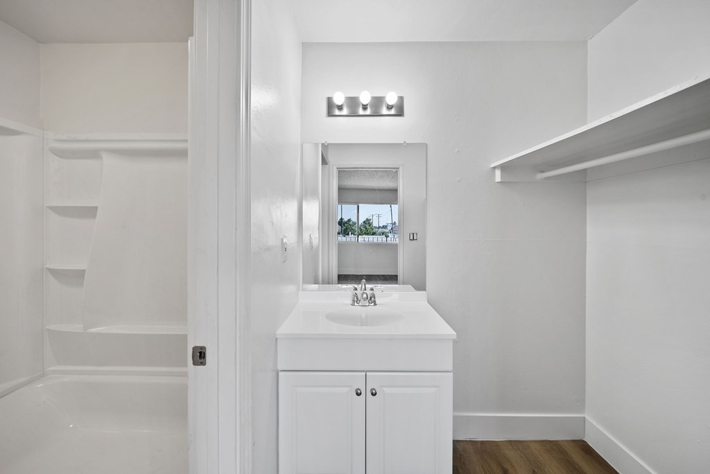 A white bathroom with a sink and mirror.