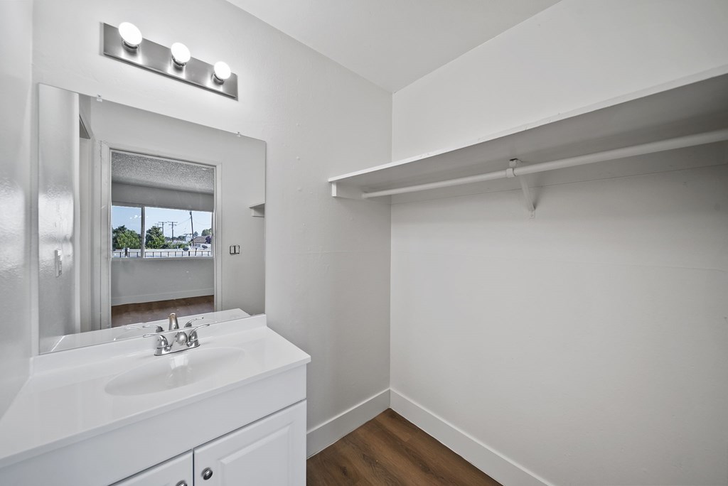 A white bathroom with a sink and mirror.