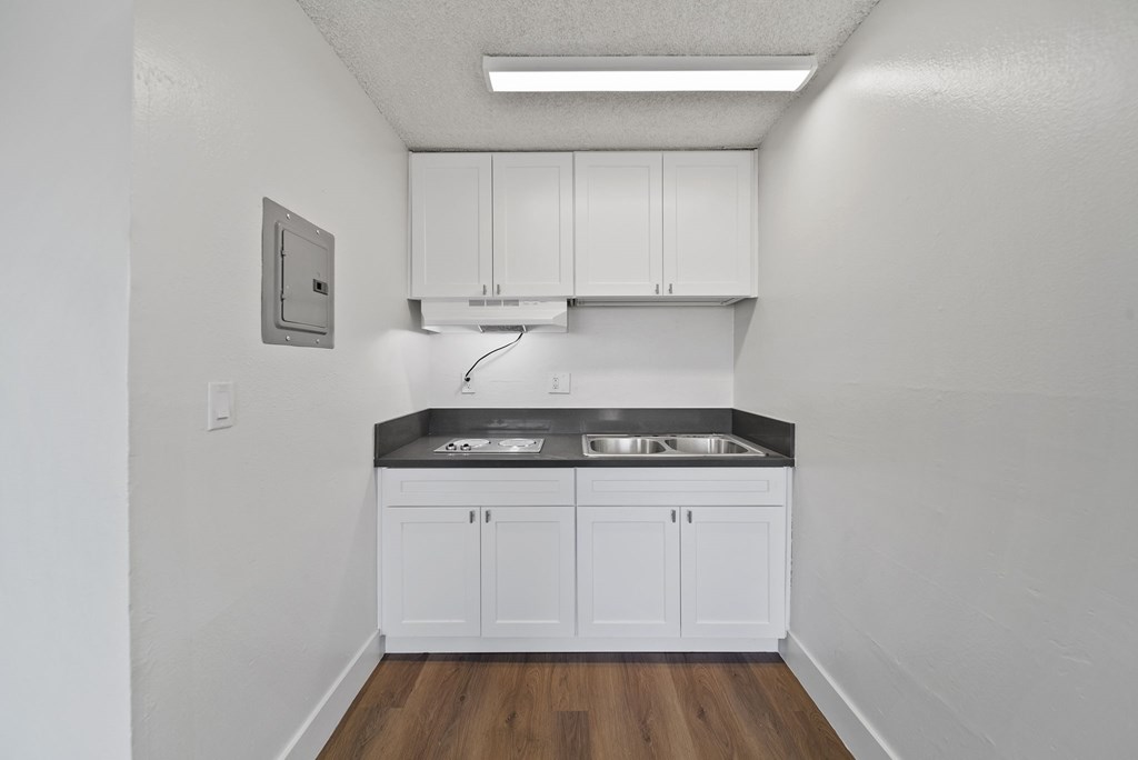 A kitchen with white cabinets and a black countertop.