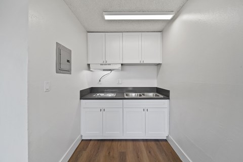 A kitchen with white cabinets and a black countertop.