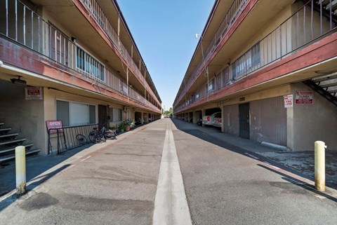 A long, narrow road separates two rows of apartment buildings.