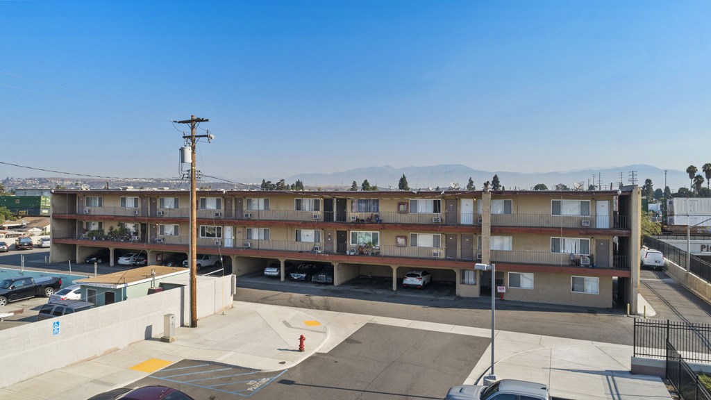 A parking lot in front of a multi-story apartment building.