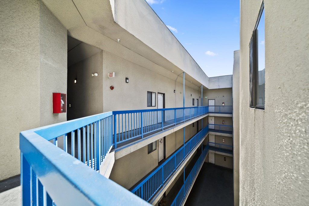 A blue railing on a balcony overlooks a courtyard.