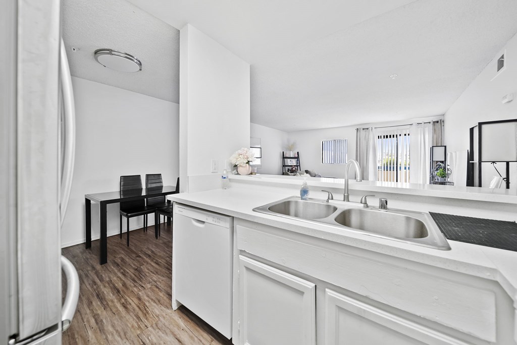 A white kitchen with a black chair and a white fridge.