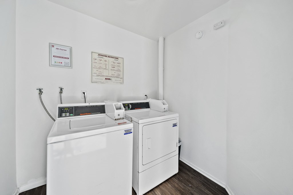 A white wall with a washing machine and dryer in front of it.