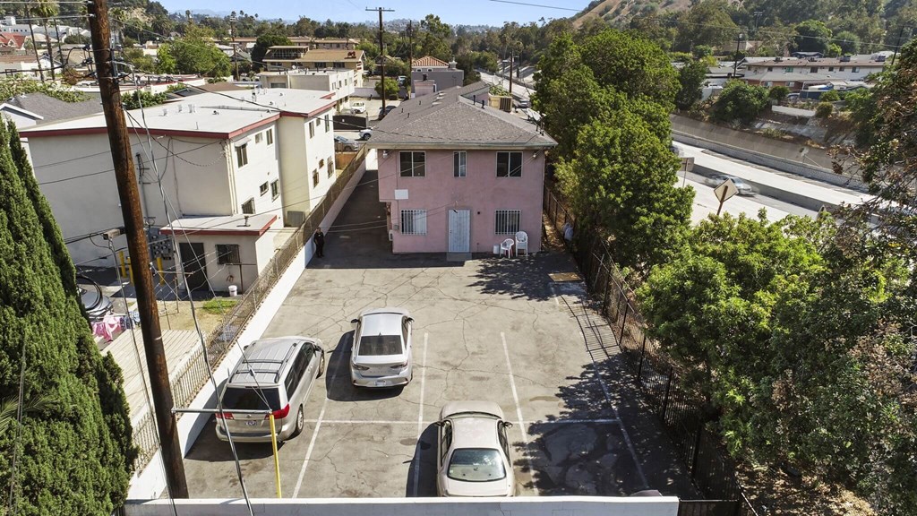 A parking lot with several cars and a pink house in the background.