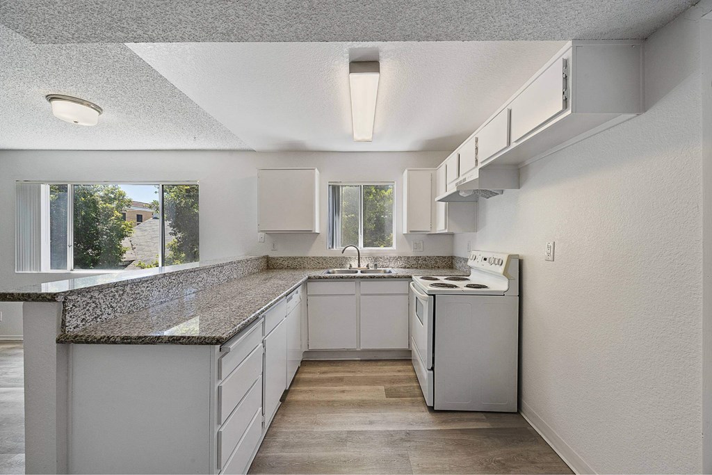 A kitchen with white cabinets and a granite countertop.