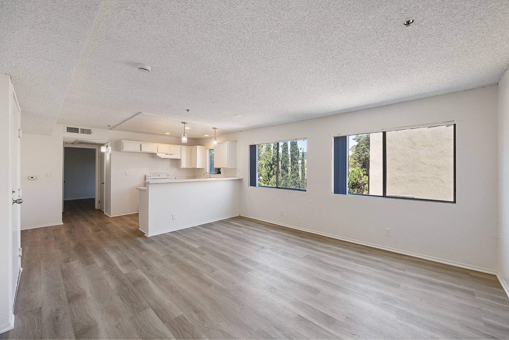 A spacious room with wooden flooring and a large window.