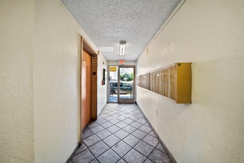 A long hallway with a brown door and a white wall.