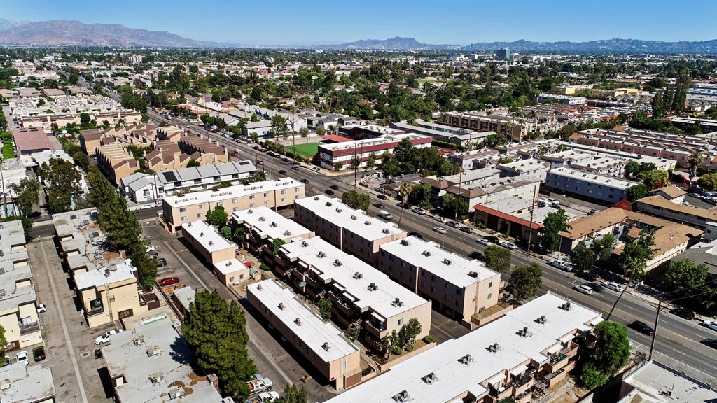 A large, modern building complex is surrounded by other buildings and trees.