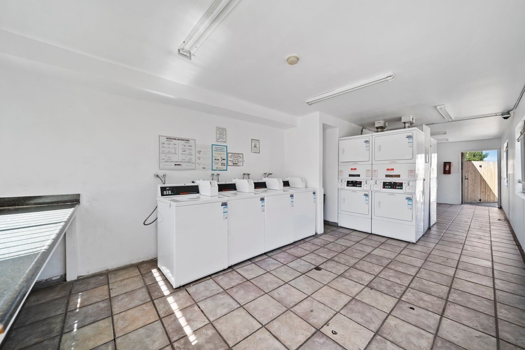 A clean, empty room with white appliances and tiled flooring.