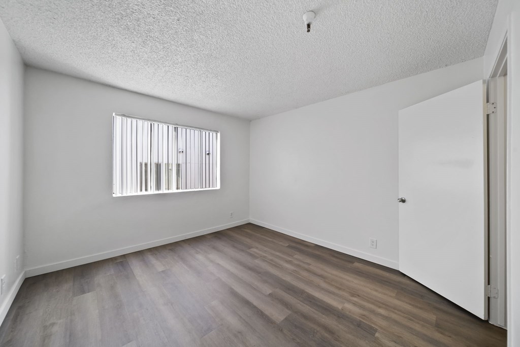A room with a window and wooden flooring.