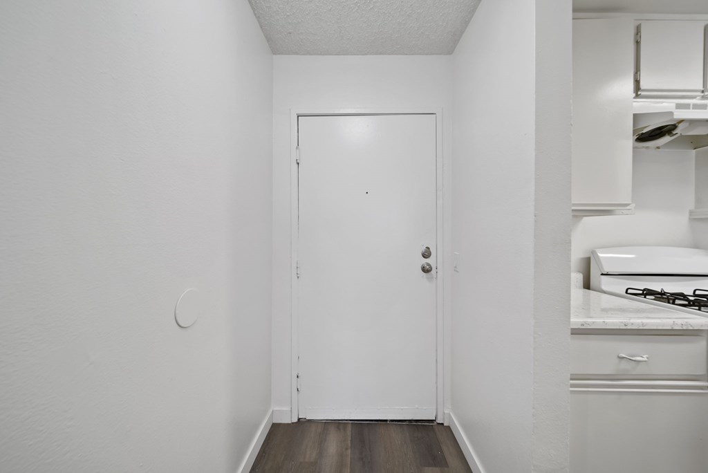 A white door is in a white room.